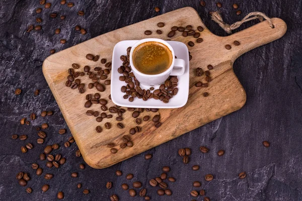 Café caliente en una taza, granos de café están dispersos cerca. Bacs oscuro — Foto de Stock