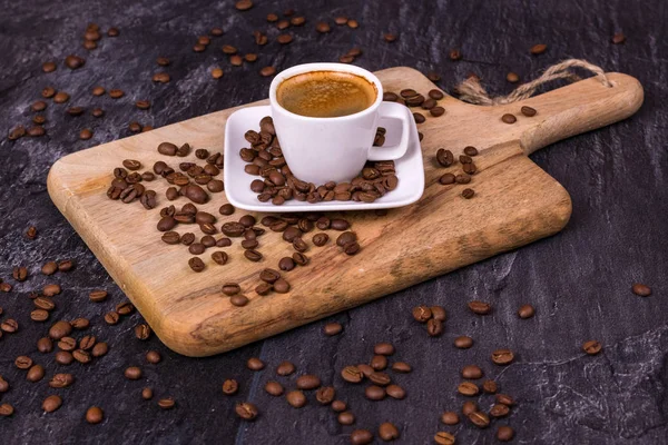 Café caliente en una taza, granos de café están dispersos cerca. Bacs oscuro —  Fotos de Stock