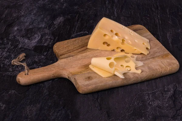 Pedazo de queso y rebanadas en una tabla de cocina de madera. ¿Qué? —  Fotos de Stock