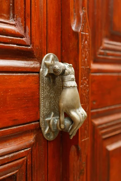 Handle for opening the door in the form of a hand