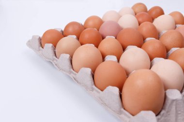 Kağıt bir kabın içinde sarı, bej ve beyaz tavuk yumurtaları. İzole et