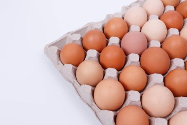 Kağıt bir kabın içinde sarı, bej ve beyaz tavuk yumurtaları. İzole et