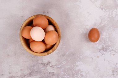 Ahşap bir tabakta kırsal yumurtalar, tabağın yanında bir yumurta. Yakın plan. Yukarıdan görüntüle