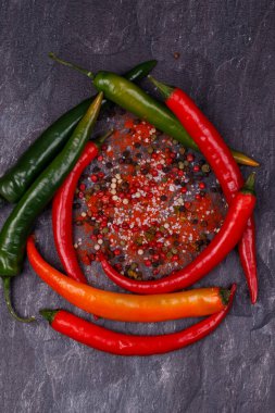 Farklı biber türleri: kırmızı biber, kuru ve bezelye. Kırmızı sarı ve yeşil biberlerin yanı sıra deniz tuzu. Tüm yerli halk karanlık bir arka planda..