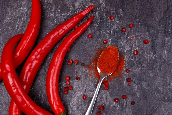 stock image Red pods of chili pepper, spoon with paprika. Top view, close-up. Dark background