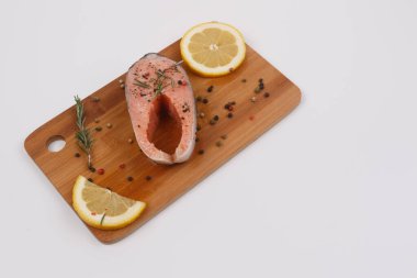 Çiğ somon bifteği, biberiye, limon ve mutfak tahtasında baharat. Yakın plan. Yukarıdan bak. İzole et