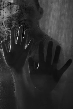 Duşta kadın ve erkeğin elleri ıslak cam üzerinde. Yakın plan. Siyah beyaz fotoğraf..