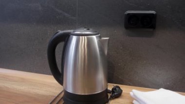 Mutfak masasında elektrikli çaydanlık. Su ısıtıcısından uzaklığa doğru kamera hareketi