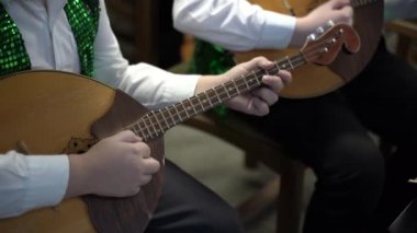 Bir çocuk domra oynuyor. Ellerini ve müzik aletini kapat. 4k