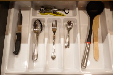 Mutfak eşyaları dolapta. Çatalların, kaşıkların, bıçağın ve güvecin üst görüntüsü