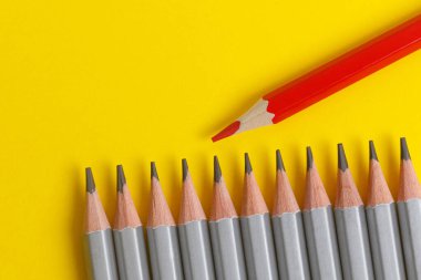 Sarı kağıtta kırmızı kalem ve gri kalemler. Lider konsepti, farklı, eşsiz
