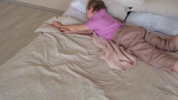 女孩在床上打滚 用毯子把自己包裹起来 侧视图 — 图库视频影像