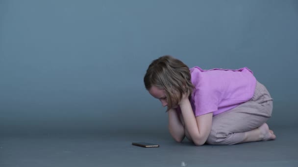 Una Chica Sentada Regazo Mira Teléfono Móvil Fondo Gris Imagen — Vídeo de stock