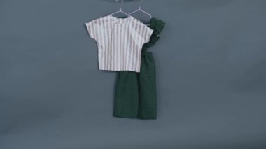 Bebek kıyafetleri. Gri arka planda yeşil elbise ve çizgili bluz. İzole et