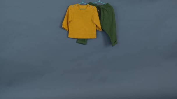 Ρούχα Μωρού Κίτρινο Πουκάμισο Και Πράσινο Παντελόνι Γκρι Φόντο — Αρχείο Βίντεο