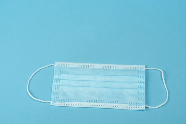 Surgical mask with rubber ear straps. Typical 3-ply surgical mask to cover the mouth and nose. Procedure mask from bacteria. Protection concept.