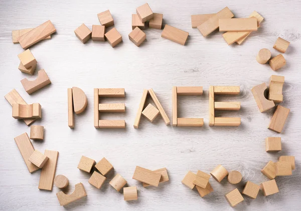 Peace building concept. Peace word written with toys building blocks on floor background.