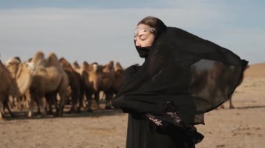 beautiful woman national black clothes,abaya walks steppe camels,desert,slow