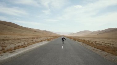 man beard mustache suit runs road,raises hand up,rejoices around mountain