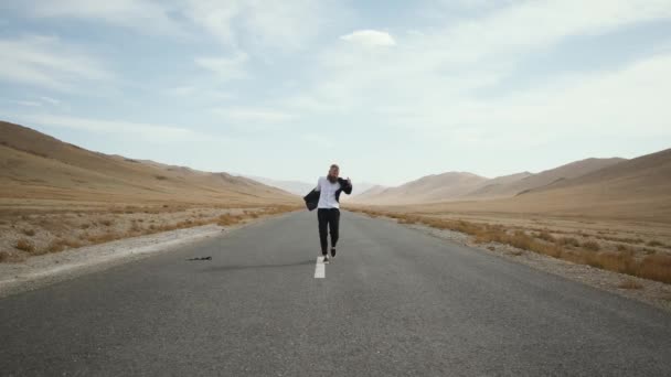 Hombre barba bigote traje va camino, lanza ropa, se regocija alrededor de la montaña — Vídeos de Stock