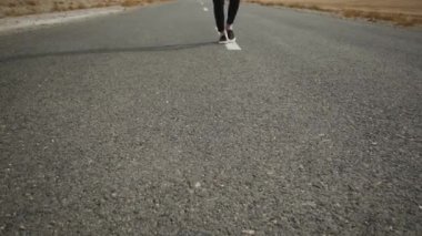Beyaz tabanlı siyah erkek ayakkabıları gri asfalta takılır. Biri yavaş yavaş, işaretli yola.