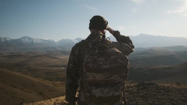 Male traveler beard military suit backpack, looks snow-capped mountains — Stockvideo