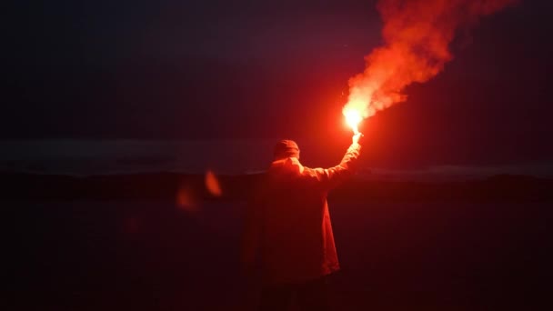 Чоловічий плащ, хвилястий червоний дим сигнал, світло, гори озера. — стокове відео