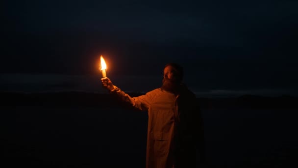 Man regenjas, zwaaiend rood rooksignaal, licht, meer bergen.reiziger nacht — Stockvideo