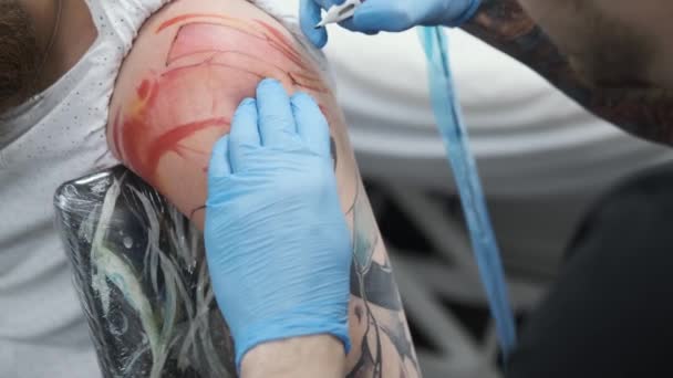 Tatuaje estudio, chico consigue tatuaje de color en su brazo, su sangrado — Vídeos de Stock