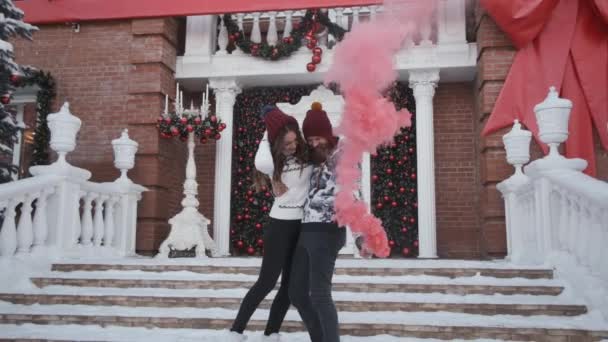 Молодая пара на Рождество, Новый год играть розовый дым граната рядом с украшенным домом — стоковое видео
