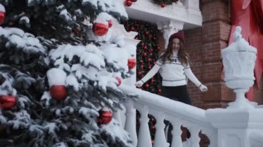 Kız mutlu yeni yılda dans ediyor, Noel 'de dekore edilmiş evin yanında Noel ağacı