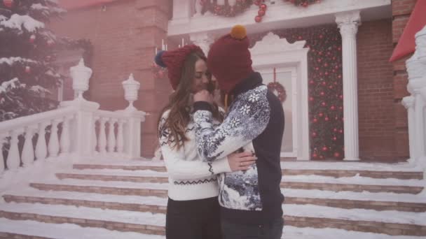 Young couple at Christmas,new year play pink smoke grenade near decorated house — Stock Video