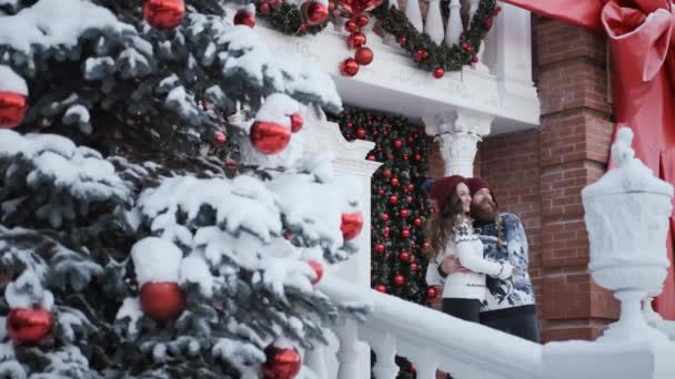 Genç aile dekore edilmiş evin yanında kucaklaşıyor. Noel ve Yeni Yıl kavramı — Stok video