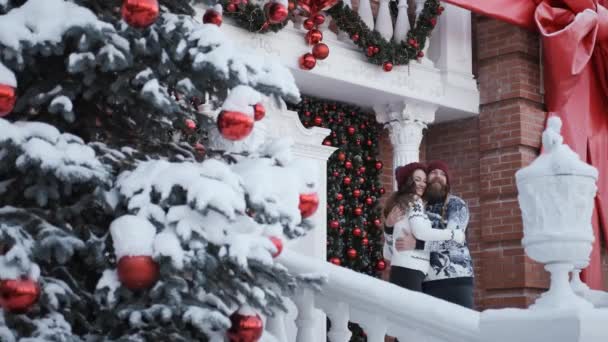 Mladá rodina objímá vedle zdobeného domu.koncept Vánoc a Nového roku — Stock video