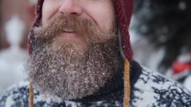 Sakallı ve bıyıklı adam kar, Noel ve yeni yıl konsepti üflüyor.