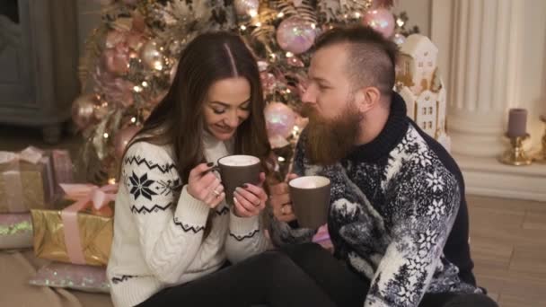 Joven familia se sienta junto a la chimenea, beber cacao concepto de año nuevo y Navidad — Vídeo de stock