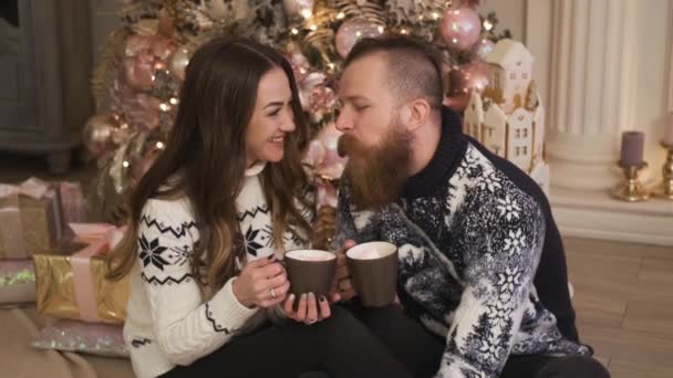 Joven familia se sienta junto a la chimenea, beber cacao concepto de año nuevo y Navidad — Vídeo de stock