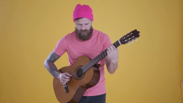 Kaukasischer Mann spielt Gitarre, hat Spaß, lächelt, gelber Hintergrund — Stockvideo