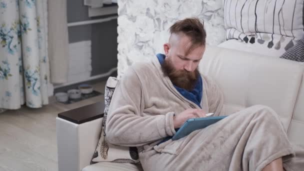 Чоловік в побуті малює на планшеті, працює вдома, дизайнер в карантині — стокове відео