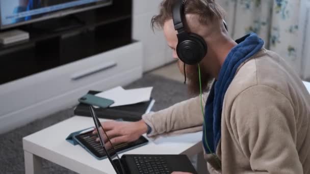 Hombre trabaja en casa en auriculares en cuarentena de la epidemia mundial de coronavirus — Vídeo de stock