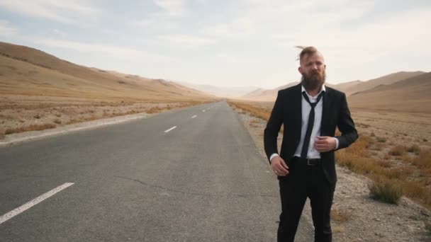 Caucasian man in office worker trying to stop car an empty scenic mountain road — Stock Video