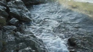Güzel mavi göl, kıyıdaki su kayalara çarpıyor.,