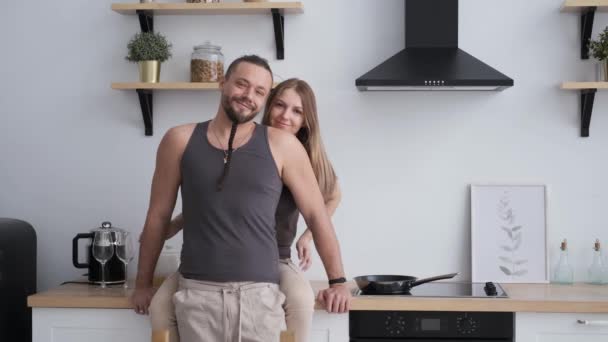 Jovem casal familiar ativo feliz na cozinha moderna, sorrindo e olhando para a câmera — Vídeo de Stock