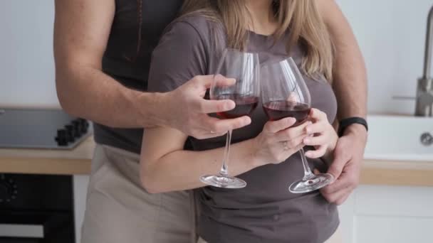 Крупный план супружеской пары, обнимающей друг друга на кухне, пьющей красное вино, 4k — стоковое видео