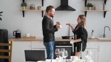 Erotik çift ev mutfağında flört ediyor ve dans ediyor. Beyaz şarap masasında.
