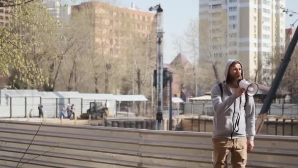 Jovem irritado protesta com sinal de stop, perto do local de construção.ruído e detritos — Vídeo de Stock