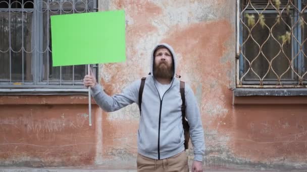 Joven hombre enojado se pone de pie con cartel cromakey, rally, crisis financiera — Vídeo de stock