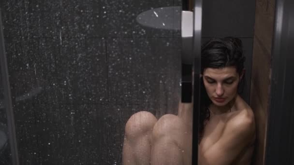 Ragazza è seduta sotto la doccia sotto l'acqua calda, triste e piangendo in bagno con doccia a casa — Video Stock