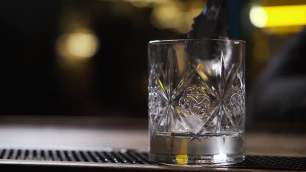 Bar there is glass,ice cubes fall into glass,bartender puts ice and takes glass — Stock Video