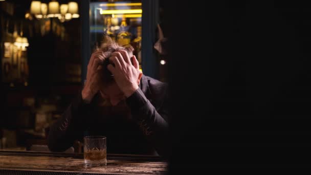 Részeg férfi a bárban egy pohár whiskey-vel, fogja a fejét, fogalom alkohol — Stock videók